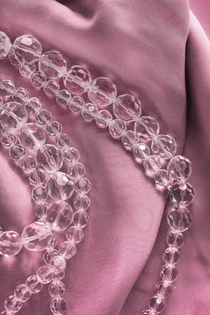Strings of crystal beads on pink silk as a backgroundの写真素材