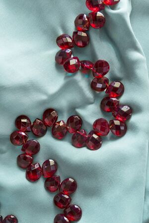 String of red crystal beads on blue silk as a backgroundの写真素材