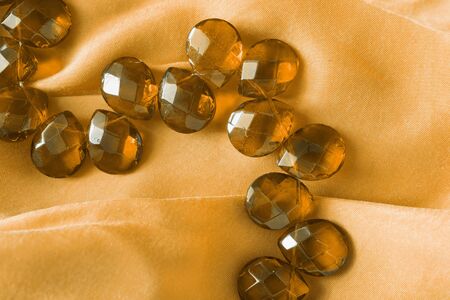 Amber beads on yellow silk as a backgroundの写真素材