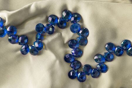 Blue crystal beads on beige silk as a backgroundの写真素材