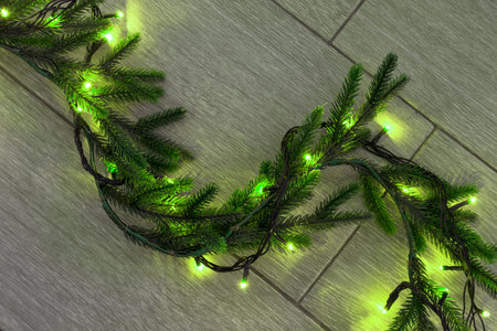Christmas tree garland with green lights on wooden floor