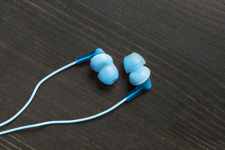 Blue wired earphones on wooden backgroundの写真素材