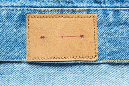 Blank brown label on blue denim as a background