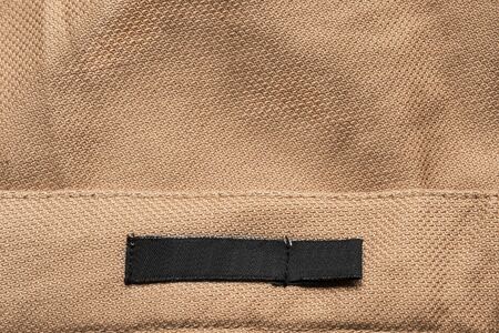 Black clothes label on beige cloth as a backgroundの写真素材