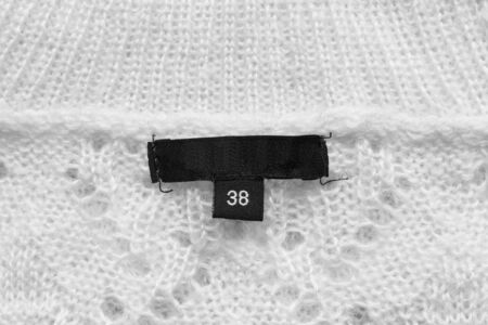 Black clothes label on white knitwear as a backgroundの写真素材