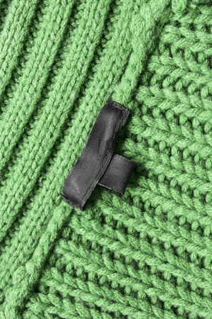 Black blank label on green knitwear as a backgroundの写真素材