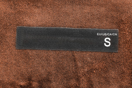 Blank S size label on brown cloth as a background