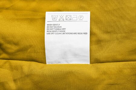 Washing instructions label on yellow cloth as a backgroundの写真素材