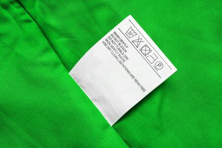 Washing instructions label on green cloth as a backgroundの写真素材