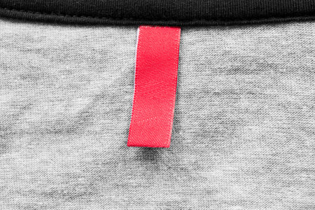 Blank red clothes label on gray knitwear as a background