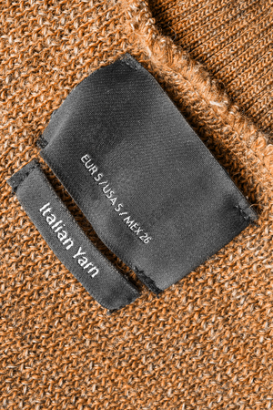 Black clothes label on brown knitting as a backgroundの写真素材