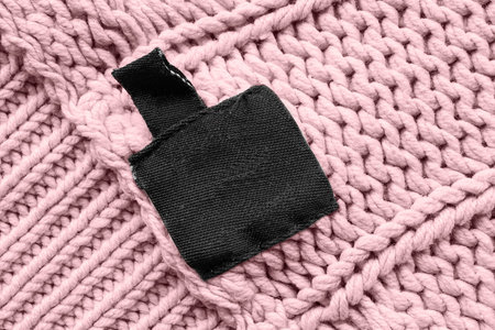 Blank black clothes label on pink knitting
