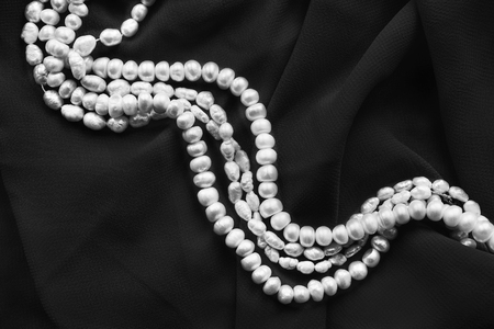 Strings of white pearl on black silk as a backgroundの写真素材