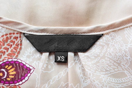 Blank black clothes label on satin as a background