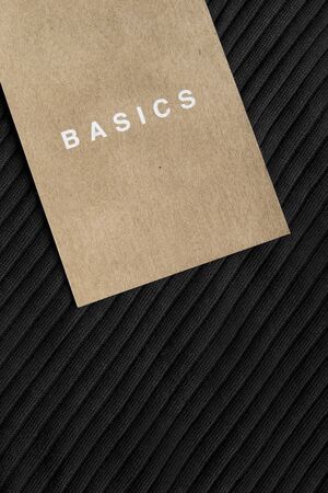 Craft paper label lettered basics on black clothの写真素材