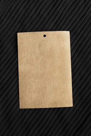 Blank craft paper label on black knitted clothの写真素材