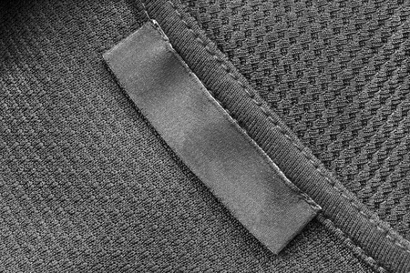 Blank clothes label on black cloth as a backgroundの写真素材