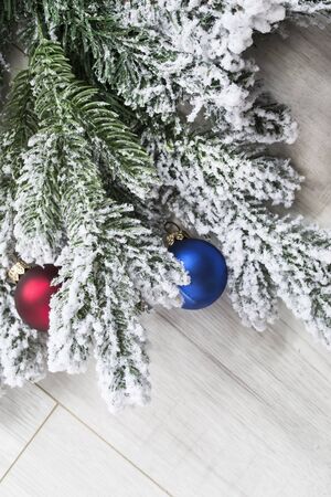 Snowy christmas tree branch with two balls on wooden backgroundの写真素材