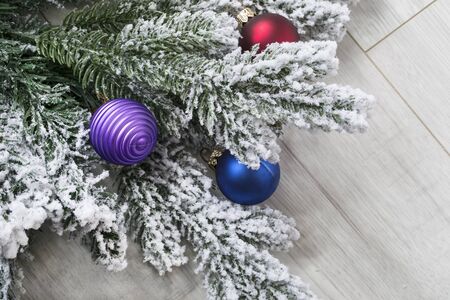Snowy christmas tree branch with balls on wooden backgroundの写真素材