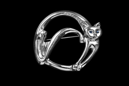 Silver brooch in the shape of a cat isolated over blackの写真素材