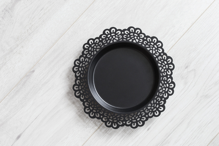 Black metal carved dish on white wooden backgroundの写真素材