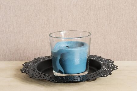 Blue candle in glass candlestick on black metal plateの写真素材