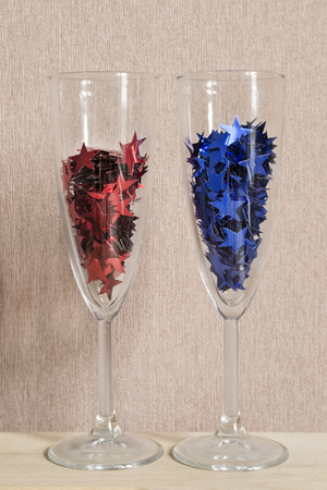 Champagne glasses full of red and blue star shaped confettiの写真素材