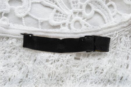 Blank clothes label on white lace as a backgroundの写真素材