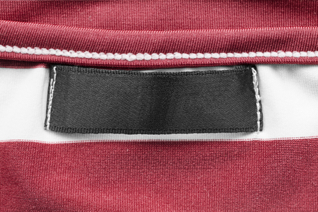 Blank black clothes label on red and white silk as a backgroundの写真素材