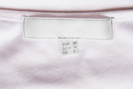 Blank white clothes label on pink cloth as a backgroundの写真素材