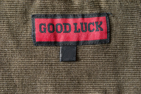 Red and black clothes label with letter good luck as a background