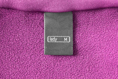 Black clothes label on pink fleece as a backgroundの写真素材