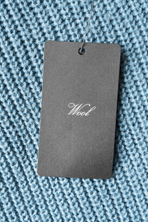 Black wool clothes label on blue cloth as a backgroundの写真素材