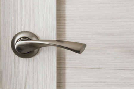 Metallic chrome door knob on wooden door as a backgroundの写真素材