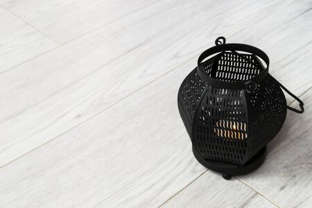 Black metal candle lamp on white wooden floor closeupの写真素材