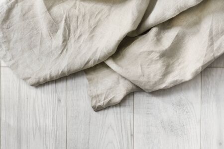 Beige folded linen on white wooden floor as a backgroundの写真素材