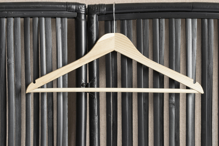 Wooden clothes rack on black rattan screen as a backgroundの写真素材