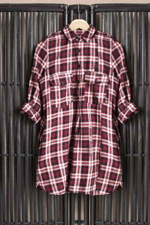 Red tartan shirt on clothes rack hanging on black wooden screenの写真素材