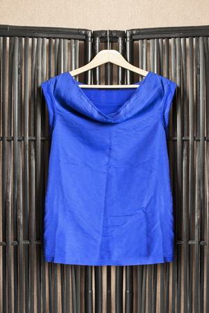 Blue silk shirt on clothes rack hanging on black bamboo screenの写真素材