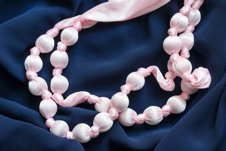 Strings of pink satin beads on blue draped cloth as a backgroundの写真素材
