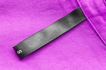 Blank black clothes label on purple cloth as a backgroundの写真素材