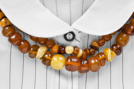 Strings of amber beads on white striped blouse closeup