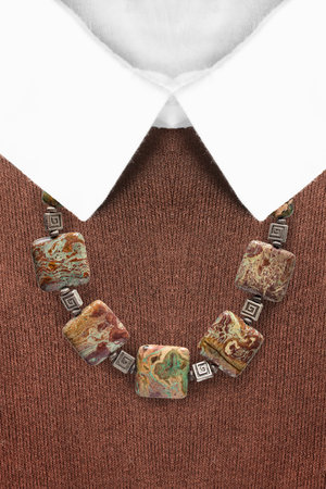 Ethnic necklace on brown pullover with white collar closeupの写真素材