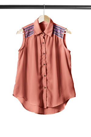 Pink sleeveless blouse on clothes rack isolated over whiteの写真素材
