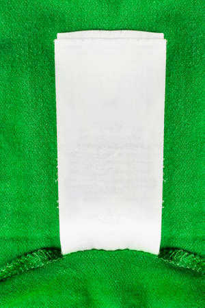 Blank white clothes label on green cloth as a backgroundの写真素材