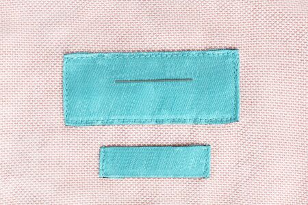 Blank cyan clothes label on pink cloth as a backgroundの写真素材
