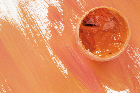 Jar of orange paint on orange brush strokes as a backgroundの写真素材