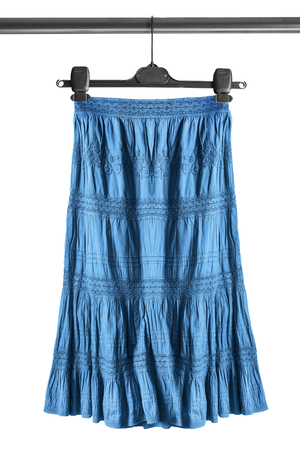 Blue ethnic skirt on clothes rack isolated over whiteの写真素材