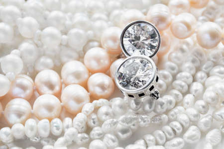 Diamond earrings and strings of pearl as a backgroundの写真素材