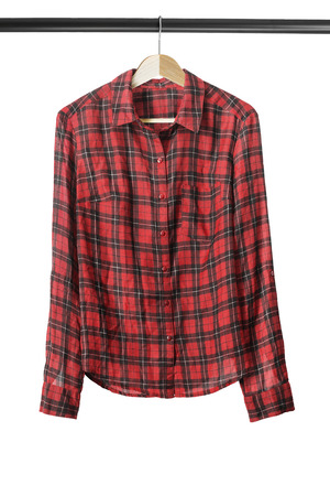 Red tartan shirt on wooden clothes rack isolated over whiteの写真素材